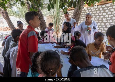 Un vieux maître d'école de village supervise des enfants dessinant avec des crayons apportés par des visiteurs à Bisaw sur une île du Nil à environ 90 km au nord d'Assouan. Banque D'Images