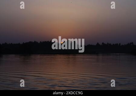 Coucher de soleil derrière les arbres le long des rives du Nil près d'Assouan, Egypte Banque D'Images