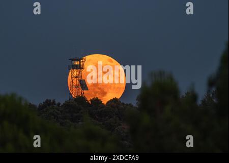 Madrid, Espagne. 21 juin 2024. La pleine lune de juin connue sous le nom de lune de fraise se lève au-dessus d'une tour d'observation de feu coïncidant avec le solstice d'été. Crédit : Marcos del Mazo/Alamy Live News Banque D'Images