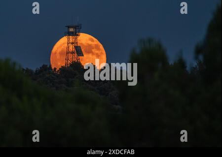 Madrid, Espagne. 21 juin 2024. La pleine lune de juin connue sous le nom de lune de fraise se lève au-dessus d'une tour d'observation de feu coïncidant avec le solstice d'été. Crédit : Marcos del Mazo/Alamy Live News Banque D'Images