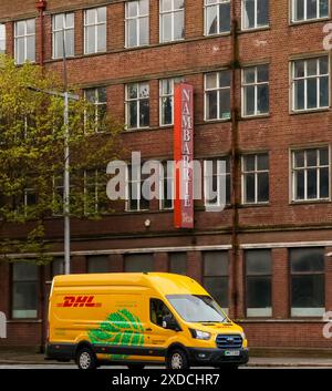 Sortie livrant DHL jaune fourgon de livraison électrique sur la route de la rue du centre-ville. Banque D'Images