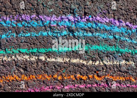 Ligne colorée de craie sur un trottoir. Tableau noir avec des lignes vibrantes peintes. Les couleurs sont bleu, vert, jaune et rouge Banque D'Images