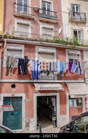 Rue de la ville de Lisbonne. Les vêtements lavés pendent du balcon et séchent à l'extérieur. Vêtements secs sur le balcon, vieilles maisons vintage, architecture authentique. Banque D'Images