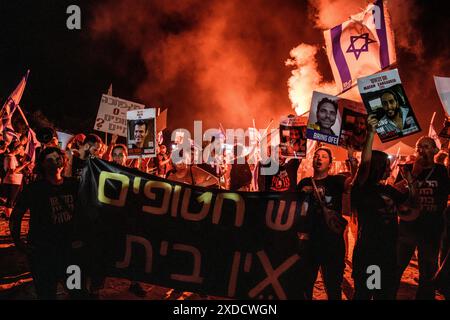 Israël. 20 juin 2024. Les manifestants se tiennent aux côtés des membres de la famille des otages israéliens Matan Zangauker et Dror ou alors qu'ils agitent le drapeau israélien et tiennent leurs photos et une pancarte qui dit : « il y a des otages, il n'y a pas de maison ». Des milliers de manifestants anti-Netanyahu ont manifesté dans les dunes à côté de la résidence du premier ministre Benjamin Netanyahu pour exiger un accord d'otages et des élections générales. Césarée, Israël. 20 juin 2024. (Matan Golan/Sipa USA). Crédit : Sipa USA/Alamy Live News Banque D'Images