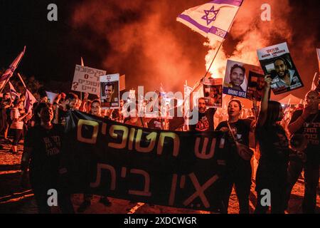 Israël. 20 juin 2024. Les manifestants se tiennent aux côtés des membres de la famille des otages israéliens Matan Zangauker et Dror ou alors qu'ils agitent le drapeau israélien et tiennent leurs photos et une pancarte qui dit : « il y a des otages, il n'y a pas de maison ». Des milliers de manifestants anti-Netanyahu ont manifesté dans les dunes à côté de la résidence du premier ministre Benjamin Netanyahu pour exiger un accord d'otages et des élections générales. Césarée, Israël. 20 juin 2024. (Matan Golan/Sipa USA). Crédit : Sipa USA/Alamy Live News Banque D'Images