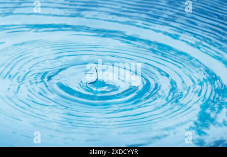 Une goutte de pluie tombe dans l'eau et laisse des cercles à la surface Banque D'Images
