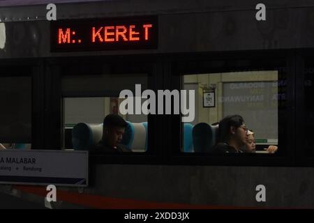 Passagers d'un train qui sont dans le train dans le matin sombre lorsque le train s'arrête à une gare Banque D'Images