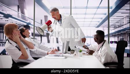 Le médecin Dominator du groupe intimidant diverses infirmières en réunion Banque D'Images