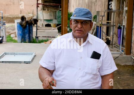 Un vieil homme portant une casquette se tient près d'une clôture rustique, profitant du plein air Banque D'Images