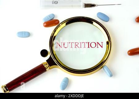 Mot NUTRITIONNEL écrit à travers une loupe sur fond blanc Banque D'Images