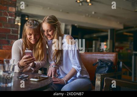 Café-restaurant, amis et femmes avec smartphone heureux dans le restaurant pour Internet, les médias sociaux et le site Web. Cafétéria, se détendre et les gens sur un téléphone pour Banque D'Images