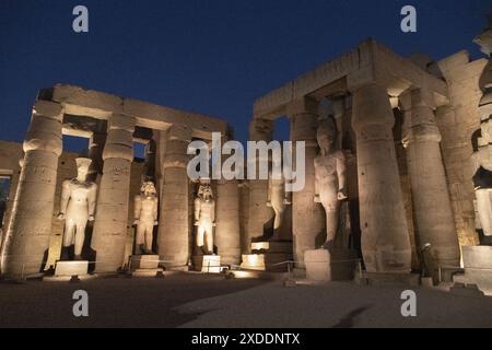 Illuminé la nuit le coin sud de la cour de Ramsès II dans le temple de Louxor présente un certain nombre de colosses de Ramsès debout entre les colonnes de papyrus. Banque D'Images