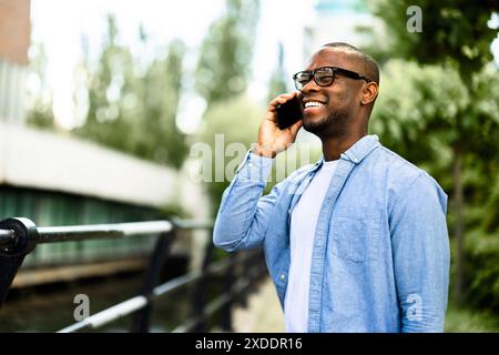 Homme d'affaires afro-américain naviguant dans les transactions financières sur smartphone en milieu urbain, mettant en valeur les compétences entrepreneuriales et le succès. Banque D'Images