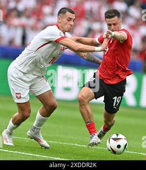 Berlin, Allemagne. 21 juin 2024. Jakub Kiwior (G), de Pologne, affronte Christoph Baumgartner, d'Autriche, lors du match du Groupe d de l'UEFA Euro 2024 opposant la Pologne à l'Autriche à Berlin, Allemagne, le 21 juin 2024. Crédit : Ren Pengfei/Xinhua/Alamy Live News Banque D'Images