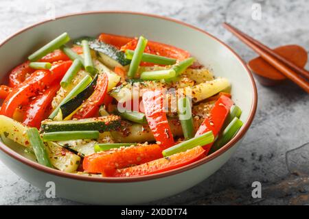 Légumes asiatiques sautés de courgettes, oignons verts et poivrons gros plan dans un bol sur la table. Horizontal Banque D'Images