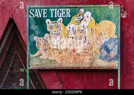 Peeling peinture sur un panneau « Save Tiger » délavé avec des photos de tigres à l'entrée de la porte Jogimahal du parc national de Ranthambore, Rajasthan, Inde Banque D'Images