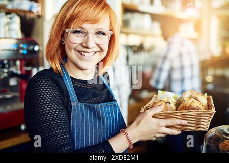 Portrait, tablier et fille avec croissant, boulanger et vendeur avec startup, petite entreprise et professionnel. Visage, personne et entrepreneur avec Fresh Banque D'Images