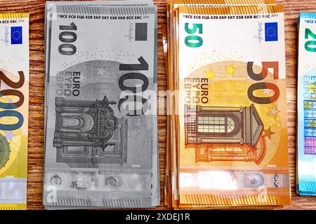 Allemagne - 22 juin 2024 : plusieurs liasses de billets en euros de différentes coupures 50, 100, 200 euros. Il symbolise l'argent noir et les pratiques financières clandestines illégales telles que le blanchiment d'argent, l'évasion fiscale et l'économie souterraine. Les billets représentent des revenus non imposés et des crimes financiers. PHOTOMONTAGE *** mehrere Bündel von Eurobanknoten in verschiedenen Nennwerten 50, 100, 200 Euro. Es symbolisiert Schwarzgeld und illegale geheime Finanzpraktiken wie Geldwäsche, Steuerhinterziehung und Schattenwirtschaft. Die Banknoten repräsentieren unversteuertes Einkommen und finanzielle Vergehen. FOT Banque D'Images