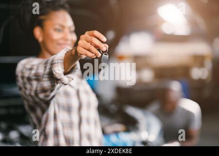 Femmes africaines heureuses montrant la clé de voiture souriant pour le retour bonne voiture saine après le service remplacer la pièce cassée. Banque D'Images