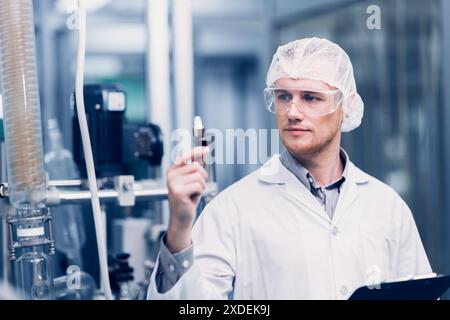 Scientifique dans Science Lab a fièrement inventé la nouvelle formule de médecine. Le personnel d'usine médicale souriant heureux avec l'extrait médical concentré de l'usine. Banque D'Images