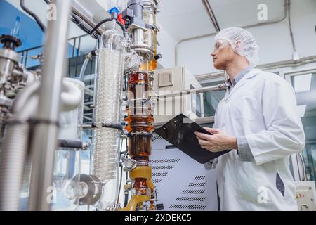 Scientifique travaillant avec des équipements dans Science Lab. Personnel d'usine médicale extraction d'huile de cannabis CBD. Usine de distillation de film mince d'huile de chanvre processus. Banque D'Images