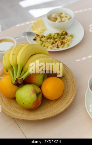 Fruits juteux mûrs dans un support d'assiette en bois sur la table de cuisine. Ustensiles de cuisine en arrière-plan. Banque D'Images