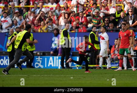 Un jeune envahisseur de terrain court sur le terrain alors que Pedro Neto (à droite) regarde le Portugais lors du match du Groupe F de l'UEFA Euro 2024 au BVB Stadion Dortmund à Dortmund, en Allemagne. Date de la photo : samedi 22 juin 2024. Banque D'Images