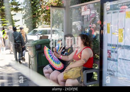 Haïfa, Israël 21 juin 2024, fierté. Les gens avec du maquillage et des drapeaux arc-en-ciel sont assis à l'arrêt de bus. Banque D'Images