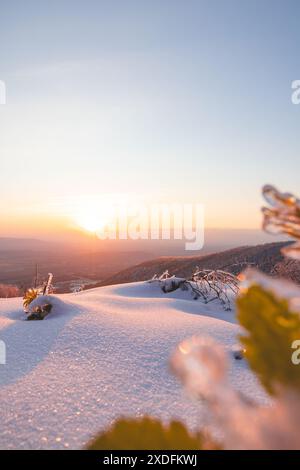 Coucher de soleil d'hiver dans les Beskids morave-silésiens, dans l'est de la République tchèque. Sommets enneigés, ciel orange-rose éclatant, nature sereine et arbres givrés Banque D'Images