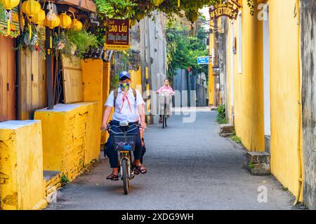 Hoi an (Hoian), Vietnam - 12 avril 2018 : écolier vietnamien faisant du vélo le long de la rue étroite de l'ancienne ville de Hoi an. Banque D'Images