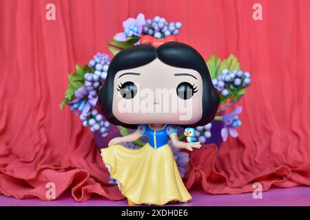 Funko Pop figurine de Disney princesse Blanche-neige avec oiseau. Rideau rose, fleurs violettes, décor, coloré, conte de fées. Banque D'Images