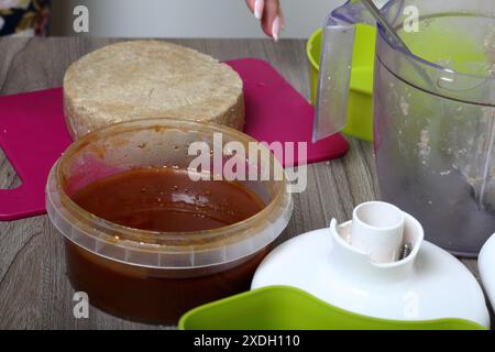 Halva à partir de miel, d'arachides et de graines de tournesol. Miel suivant dans le récipient. Ingrédients et outils pour la fabrication de halva. Banque D'Images