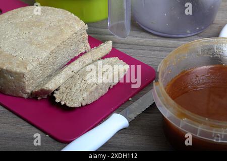 Halva tranchée de miel, d'arachides et de graines de tournesol. Miel suivant dans le récipient. Ingrédients et outils pour la fabrication de halva. Banque D'Images