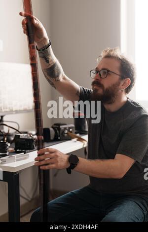 Photographe examinant des négatifs de film dans une pièce bien éclairée Banque D'Images