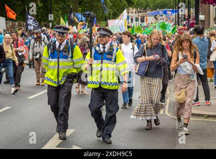 Londres, Royaume-Uni - 22 juin 2024 : deux agents de la police métropolitaine transportent une caméra vidéo pour enregistrer la manifestation Restore nature Now à Londres, au Royaume-Uni Banque D'Images