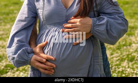 Photo de grossesse : homme et femme tenant le ventre enceinte en attendant bébé. Famille heureuse tenant le ventre gros plan. Aucune face. Couple amoureux. Banque D'Images