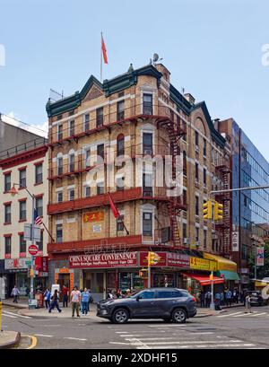 NYC Chinatown : 1 Division Street est des appartements au-dessus des magasins au coin de Catherine Street, avec des balcons en fer ; un drapeau chinois flotte du toit. Banque D'Images