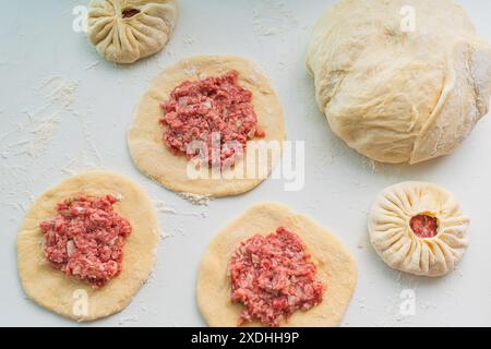 Cuisson des tartes avec de la viande hachée. La viande est étalée sur des morceaux de pâte ronds. Photo de haute qualité Banque D'Images