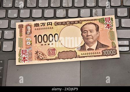 Dans cette illustration photo, un échantillon d'un billet de banque japonais de 10 000 yens est placé sur le clavier d'un ordinateur portable. Pour réduire le risque de contrefaçon, le ministère des Finances et la Banque du Japon mettront en circulation de nouveaux billets de 1 000, 5 000 et 10 000 yens au début du mois de juillet 2024. Banque D'Images