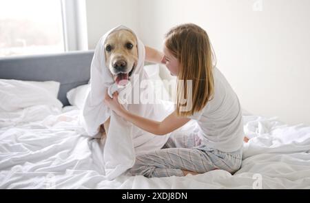 Joyeuse jeune fille s'amusant avec son animal de compagnie Golden Retriever, enveloppé dans Une couverture Banque D'Images