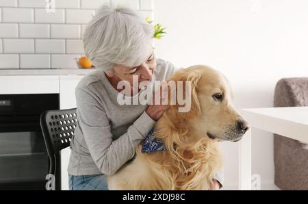 Joyeuse vieille dame caressant son adorable chien Golden Retriever avec Un sourire Banque D'Images