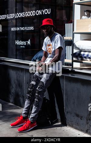 Jeune homme noir portant une casquette rouge assortie à des baskets rouges, Londres, Angleterre, Royaume-Uni. Banque D'Images