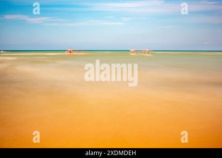 Photographie longue exposition d'Omaha Beach en Normandie, France, mettant en valeur les eaux calmes de la plage et l'atmosphère sereine sous un ciel bleu clair. Banque D'Images