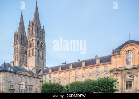 L’historique Abbaye des hommes et l’Hôtel de ville (à droite), à Caen, présentent des flèches gothiques contre un ciel serein. Banque D'Images