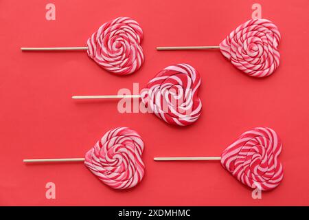 Composition avec sucettes en forme de coeur sur fond rouge. Célébration de la Saint-Valentin Banque D'Images