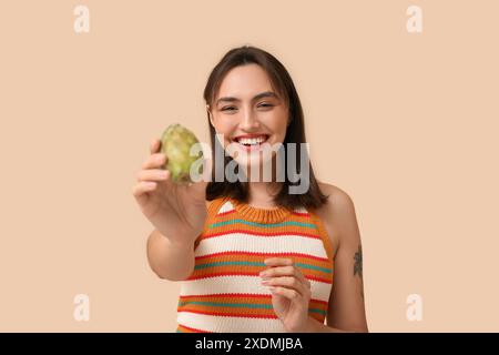 Belle jeune femme avec de la poire de barbarie fraîche sur fond beige Banque D'Images