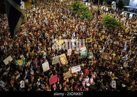 Tel Aviv, Israël. 22 juin 2024. Une foule de manifestants tient des pancartes sous le pont Begin avec les familles de l'otage pendant la manifestation. Plus de 100 000 Israéliens ont manifesté à Kaplan avec les familles d'otages contre le premier ministre Benjamin Netanyahu, exigeant un accord immédiat sur les otages et un cessez-le-feu, suite au rassemblement, les manifestants avaient déclenché un feu de camp devant le « Metzudat Ze'ev » - le siège historique du Likoud, provoquant des affrontements avec la police israélienne. Crédit : SOPA images Limited/Alamy Live News Banque D'Images