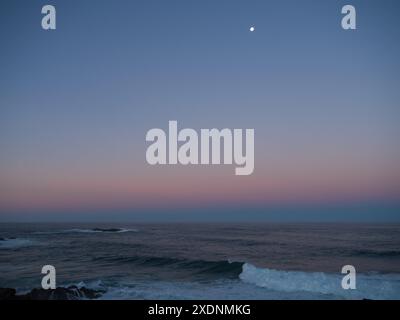 Magnifique ciel rose orange coincé entre des couches de bleu, coucher de soleil reflété dans les nuages à l'est au-dessus de l'océan Pacifique, Nouvelle-Galles du Sud Australie Banque D'Images