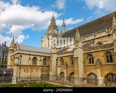 Des fleurs décorent un jardin à l'extérieur de l'abbaye de Westminster avec l'emblématique Big Ben au loin à Londres, Angleterre, Royaume-Uni. Banque D'Images