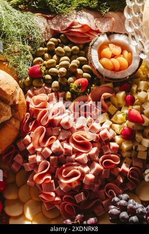 Une charcuterie vibrante avec des viandes variées, des fromages, des olives, des fruits et du pain en vue rapprochée Banque D'Images